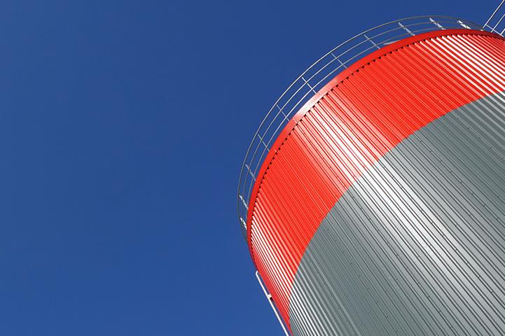 gray and red storage tank against a blue sky
